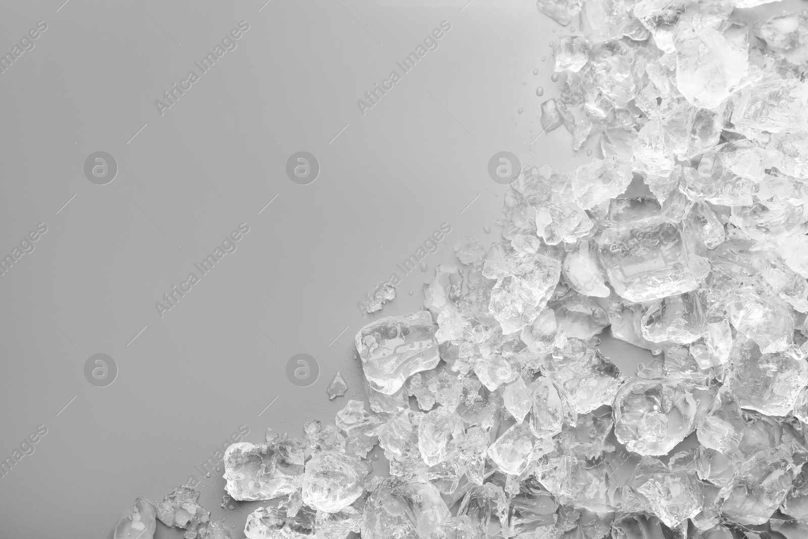 Photo of Pieces of crushed ice on grey background, top view. Space for text