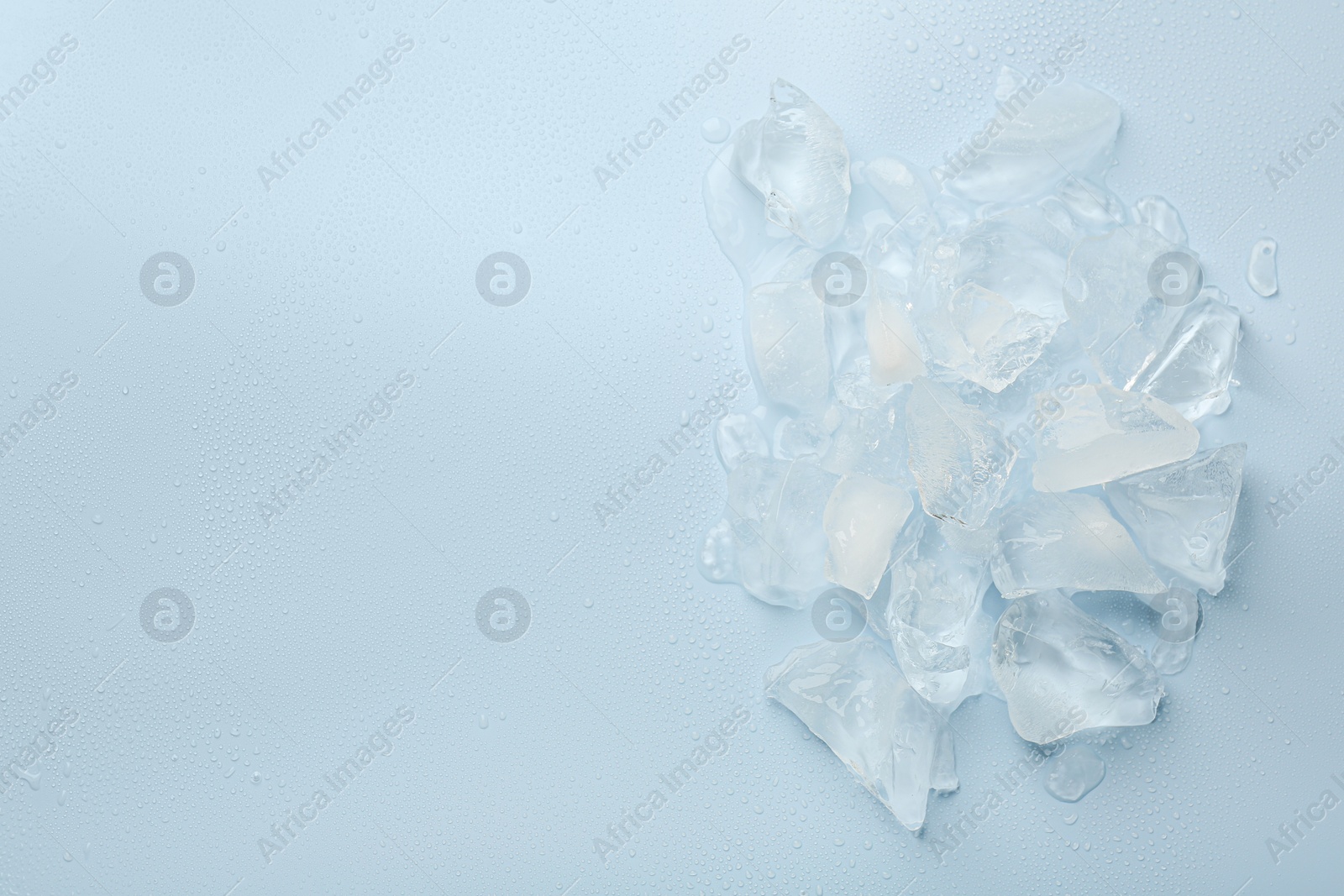 Photo of Pieces of crushed ice on light blue background, top view. Space for text