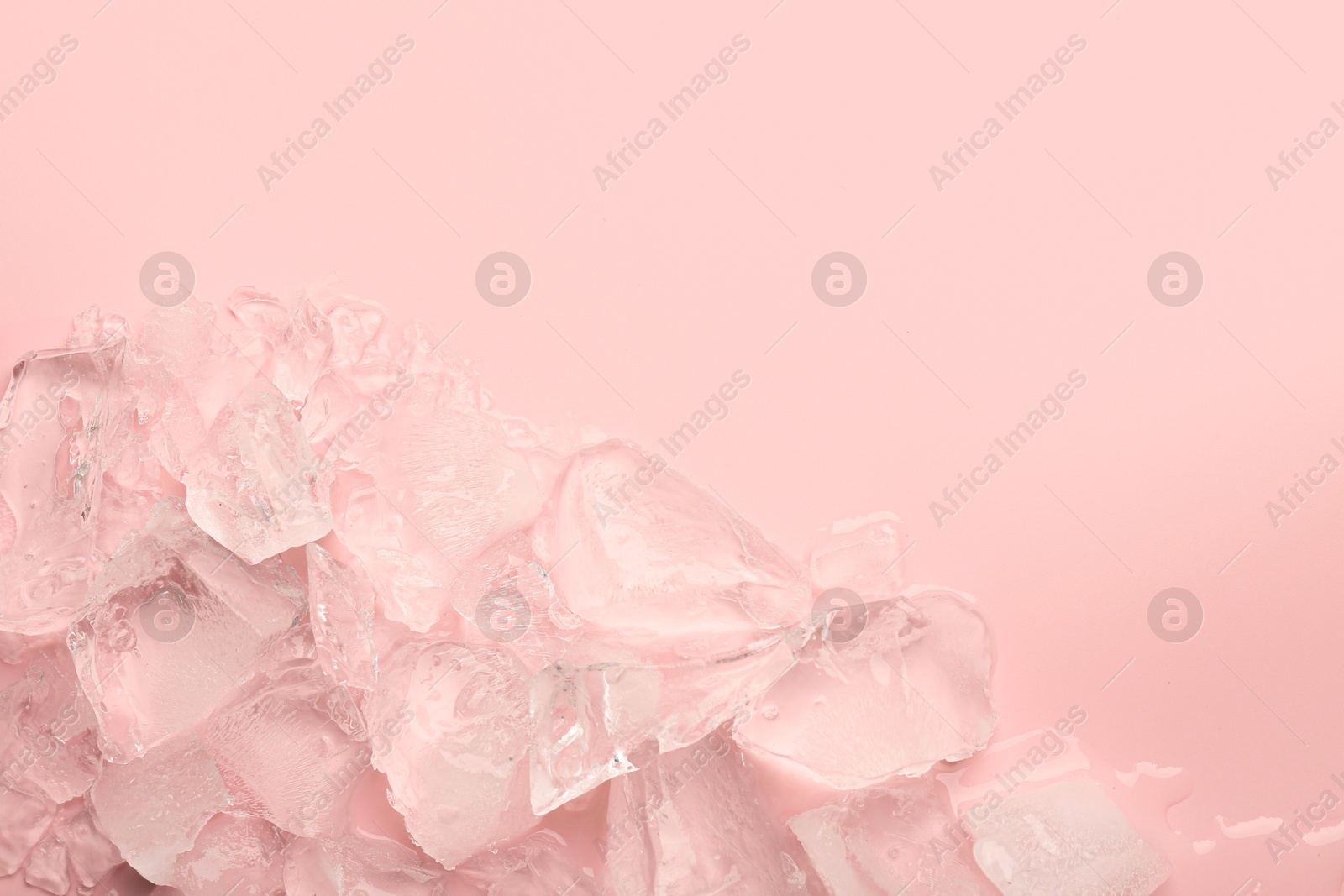 Photo of Pieces of crushed ice on pink background, top view. Space for text