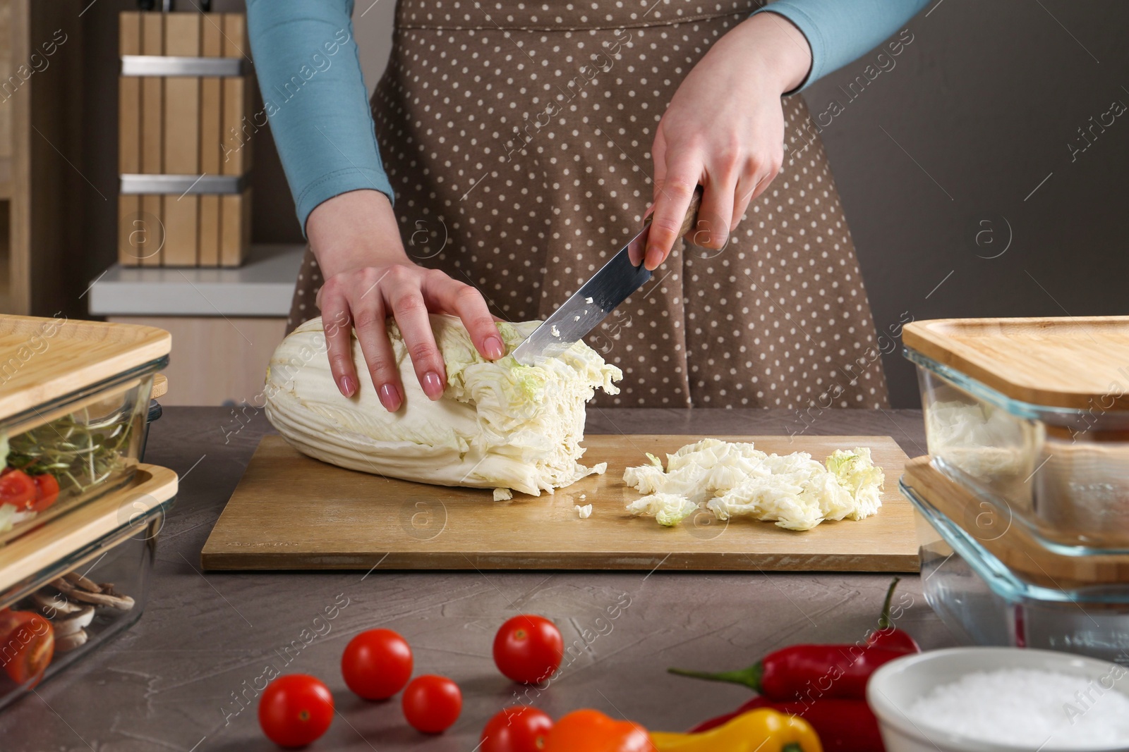 Photo of Healthy food. Woman cutting Chinese cabbage at grey table, closeup