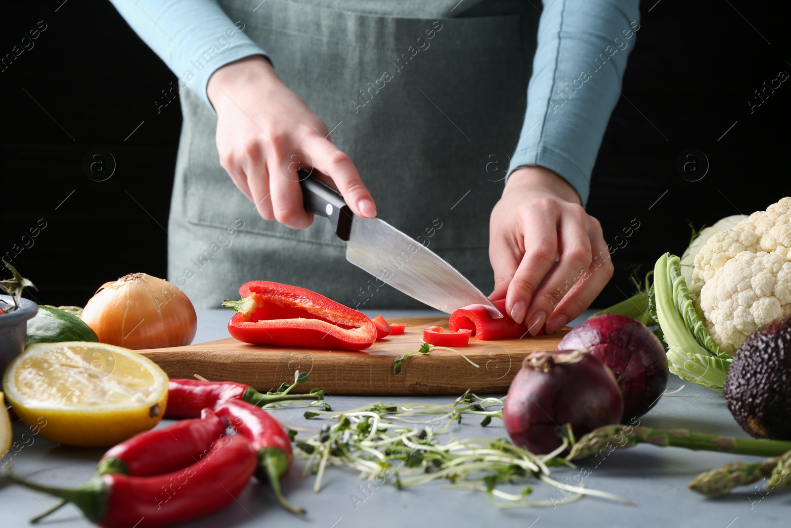 Photo of Healthy food. Woman cutting pepper at grey table, closeup