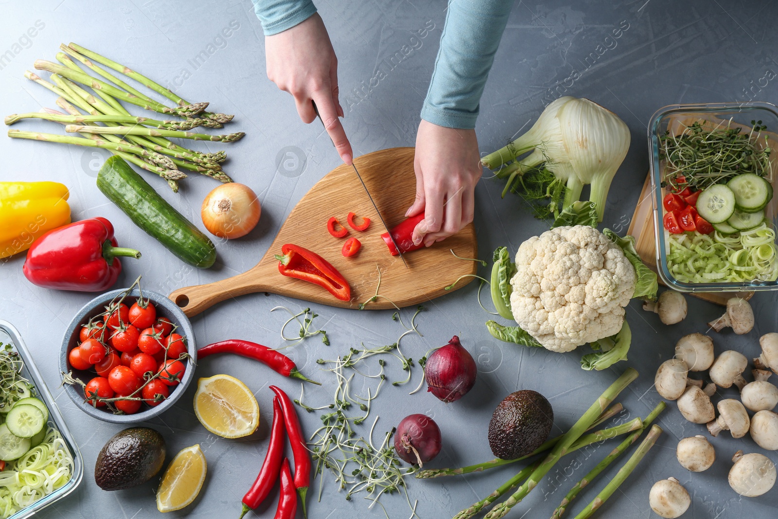 Photo of Healthy food. Woman cutting pepper at grey table, top view