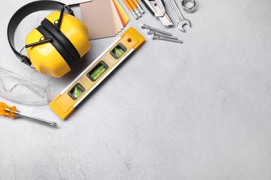 Flat lay composition with building level and other construction tools on grey table, space for text