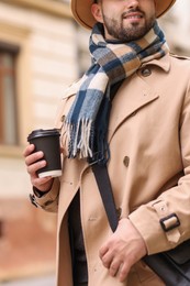 Photo of Smiling man in warm scarf with paper cup outdoors, closeup