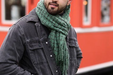 Photo of Smiling man in warm scarf on city street, closeup