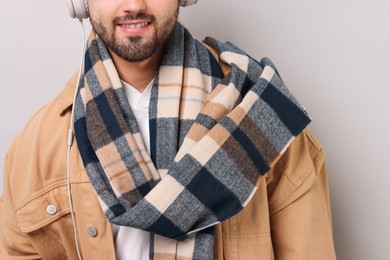 Smiling man in warm scarf on light grey background, closeup