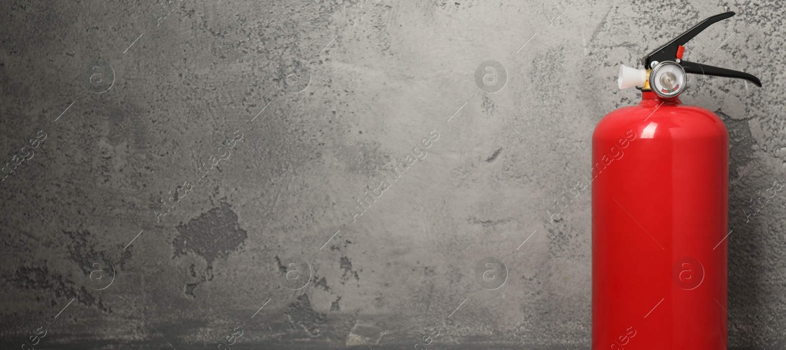 Photo of Fire extinguisher on grey textured background, space for text