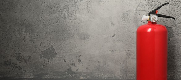 Photo of Fire extinguisher on grey textured background, space for text