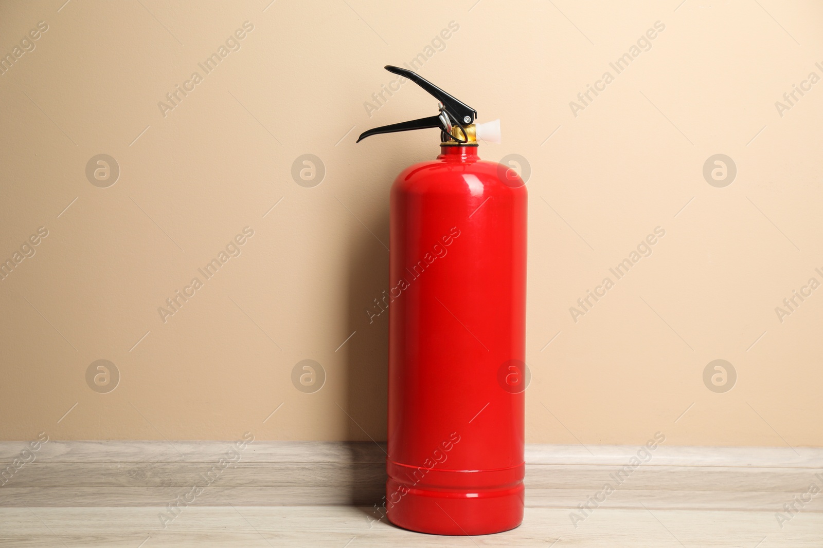 Photo of One fire extinguisher on floor near beige wall