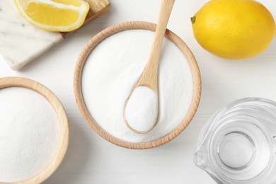 Photo of Baking soda, vinegar and lemons on white wooden table, flat lay