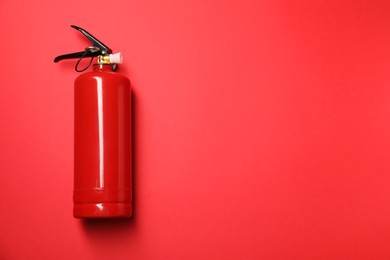 Photo of One fire extinguisher on red background, top view. Space for text