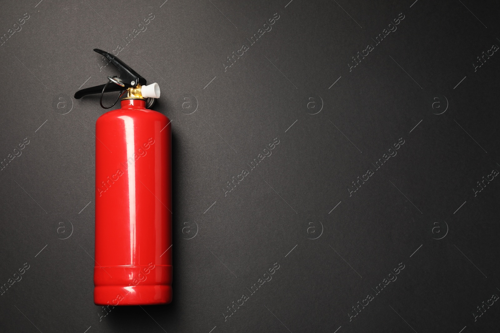 Photo of One red fire extinguisher on dark gray background, top view. Space for text