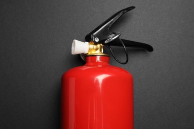 Photo of One red fire extinguisher on dark gray background, top view