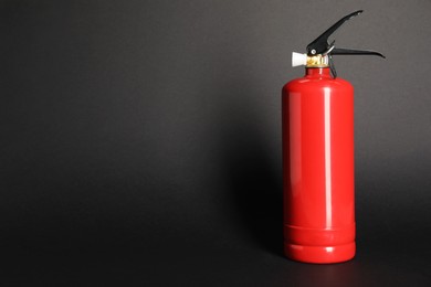 Photo of One red fire extinguisher on dark gray background, space for text