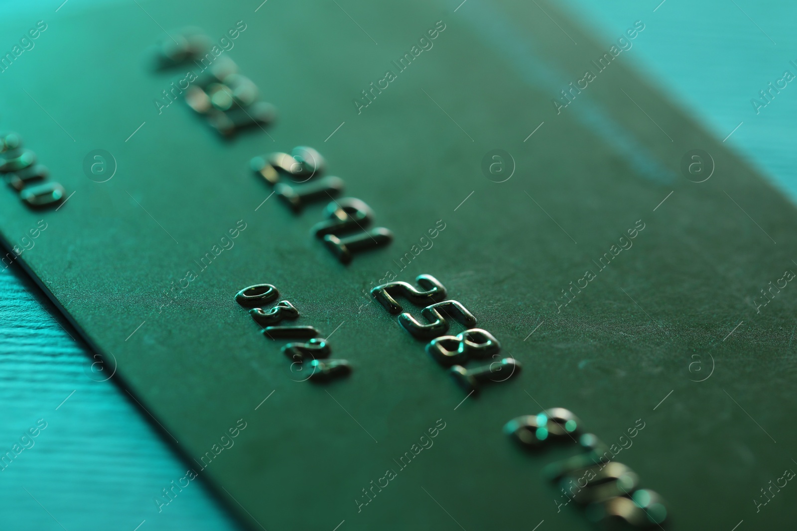 Photo of One credit card on turquoise background, macro view