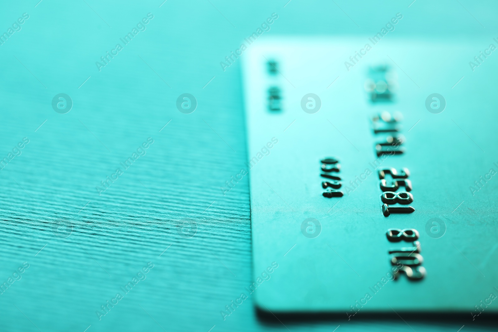 Photo of One credit card on turquoise background, closeup. Space for text