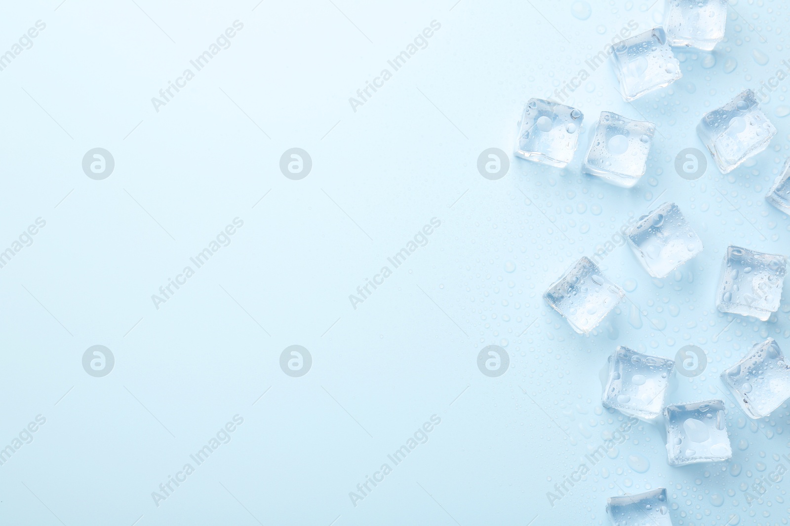 Photo of Crystal clear ice cubes on light blue background, flat lay. Space for text