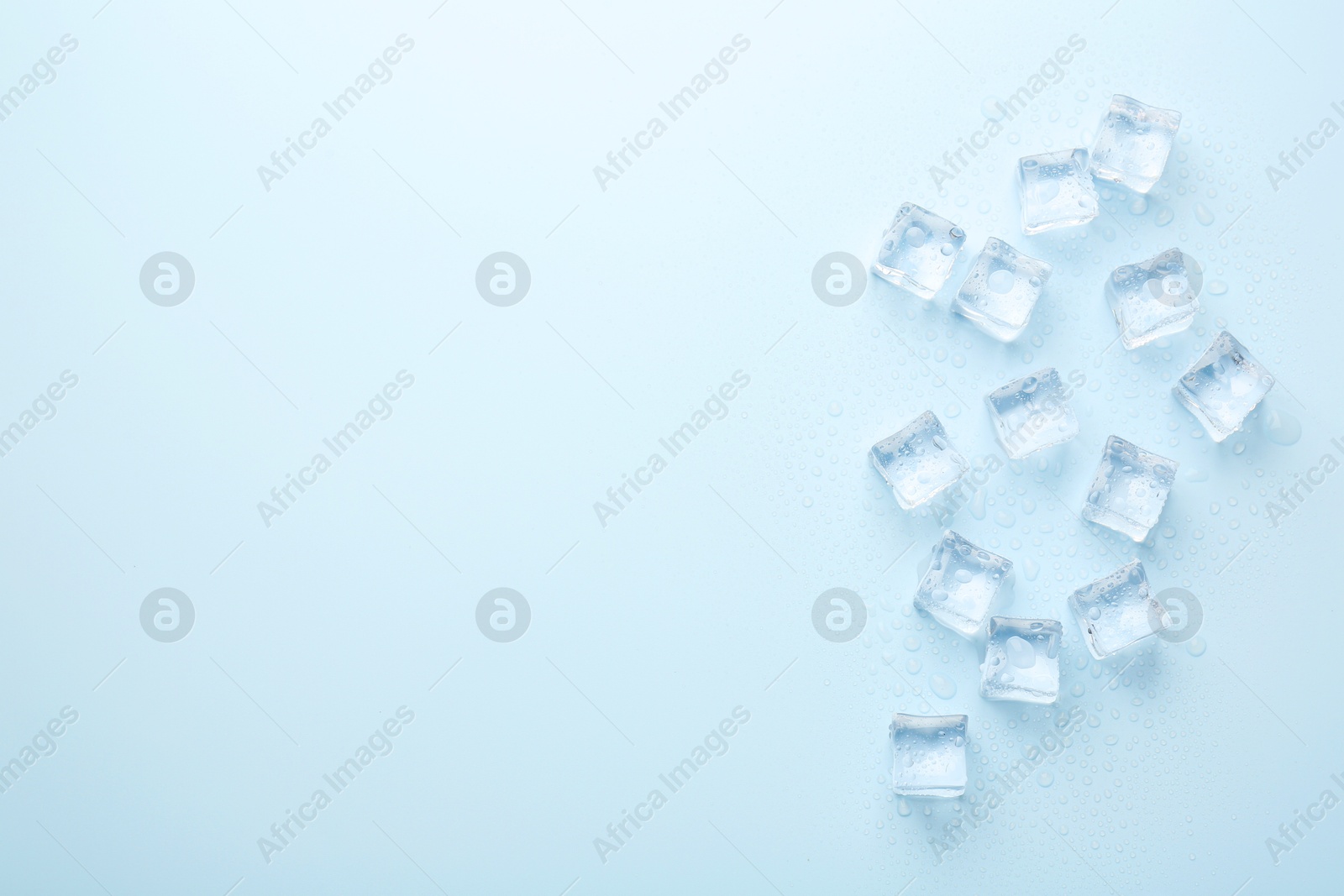 Photo of Crystal clear ice cubes on light blue background, flat lay. Space for text