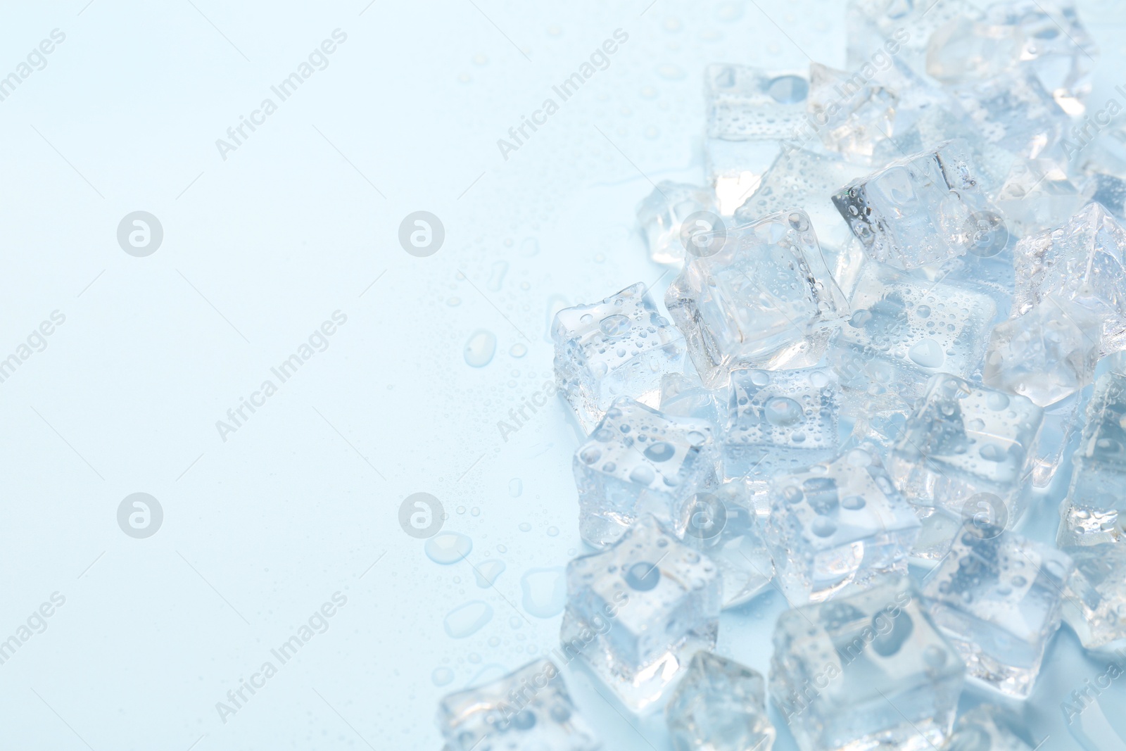 Photo of Crystal clear ice cubes on light blue background, flat lay. Space for text