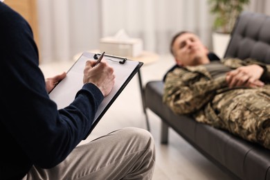 Photo of Professional psychotherapist working with military man in office