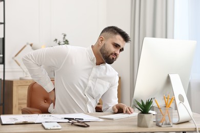 Man suffering from back pain in office. Symptom of poor posture