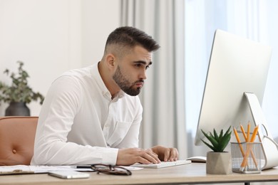Young man with poor posture working at table in office