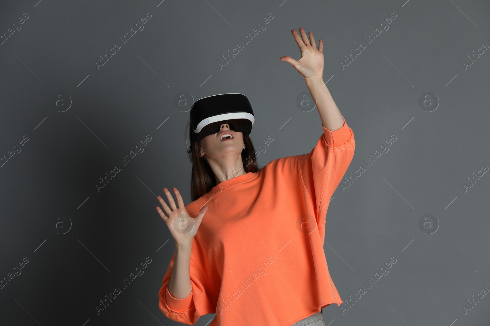 Photo of Surprised woman using virtual reality headset on gray background