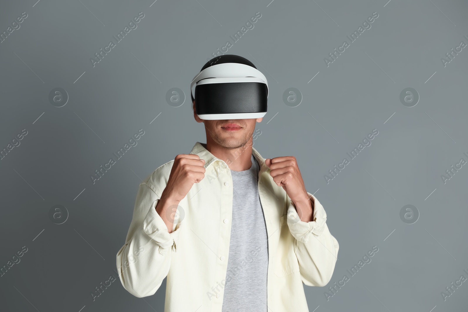 Photo of Man using virtual reality headset on gray background