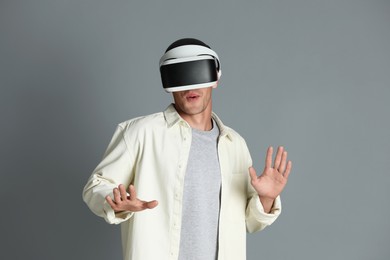 Photo of Surprised man using virtual reality headset on gray background