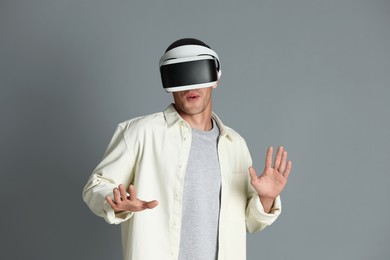 Surprised man using virtual reality headset on gray background