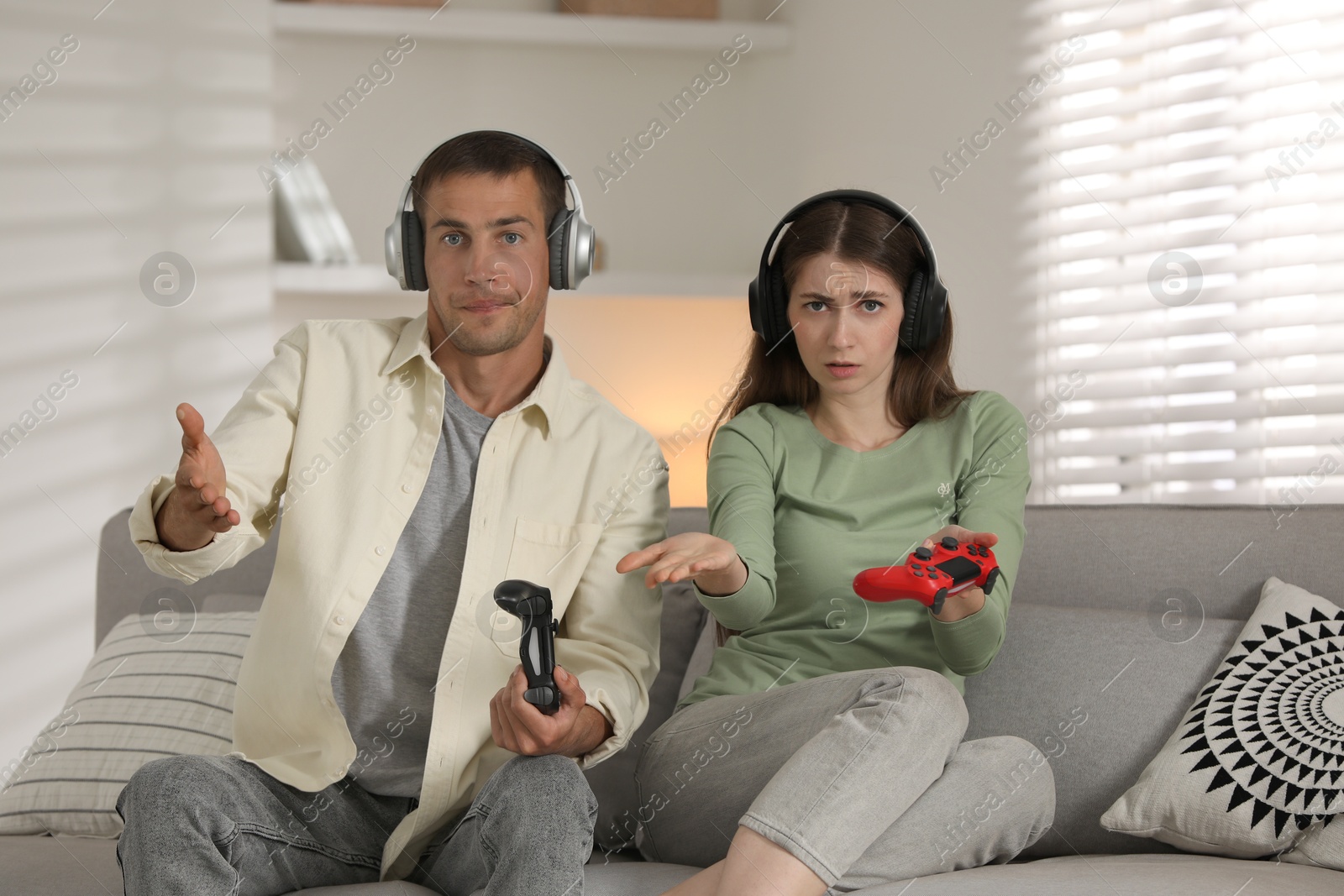 Photo of Couple playing video games with controllers at home