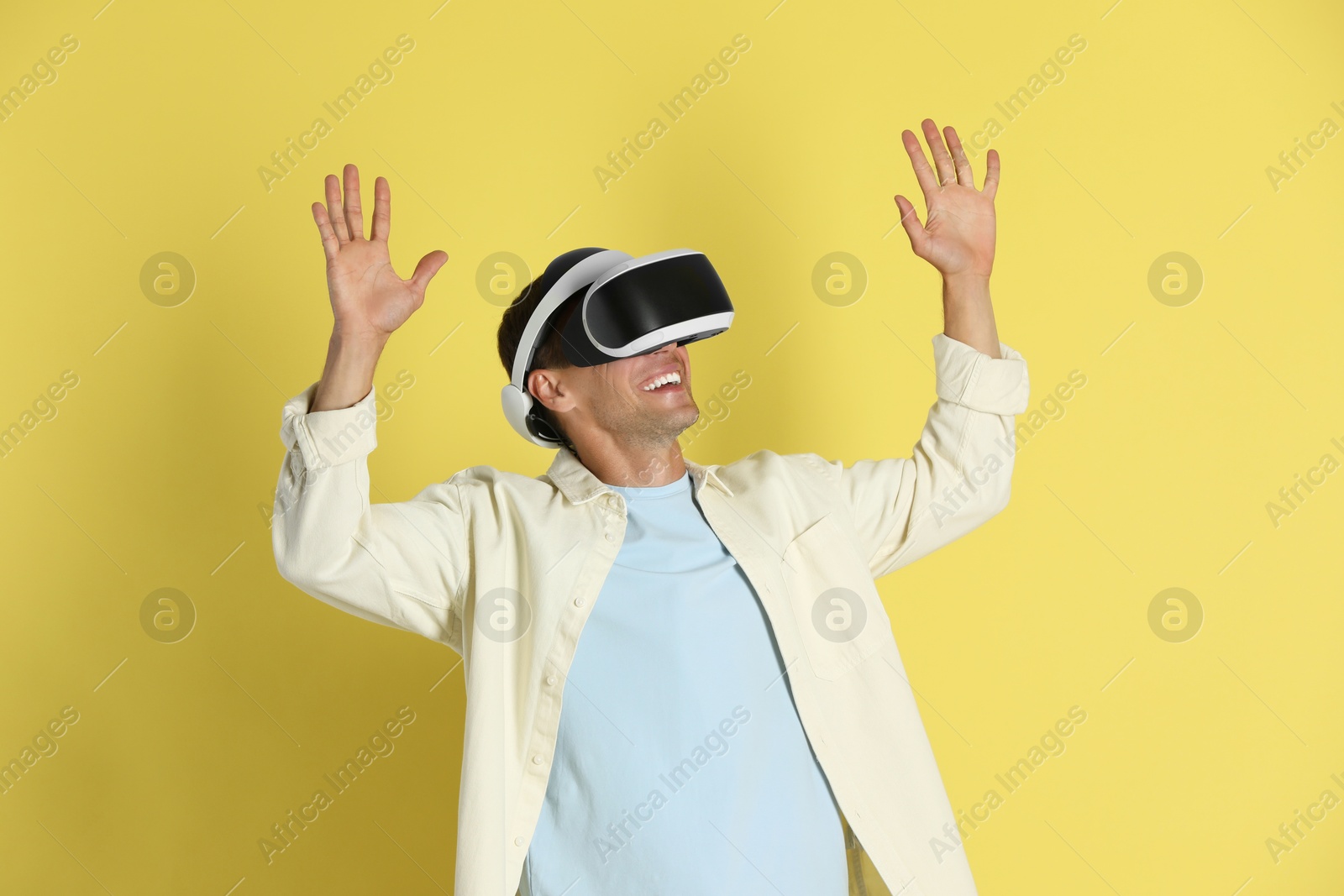 Photo of Smiling man using virtual reality headset on yellow background