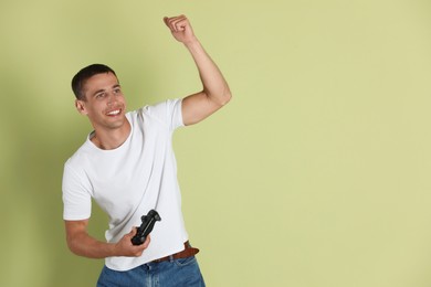 Photo of Happy man with controller on light green background, space for text