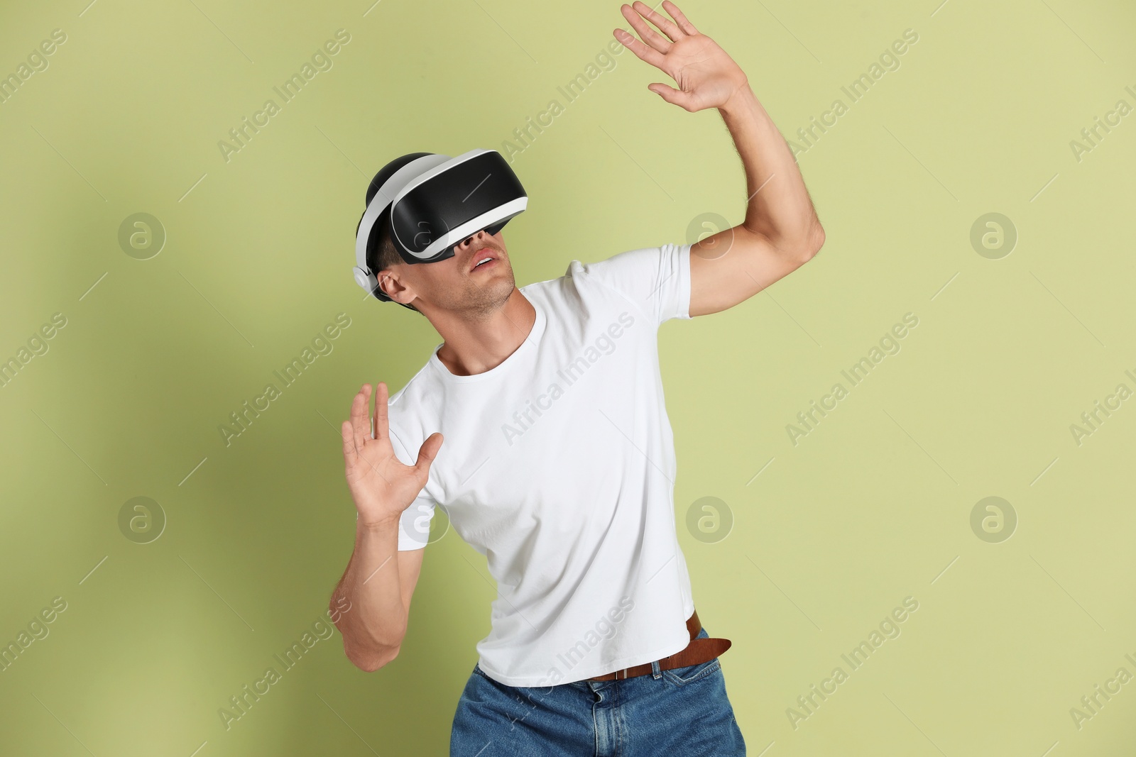 Photo of Man using virtual reality headset on light green background