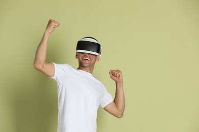 Photo of Smiling man using virtual reality headset on light green background