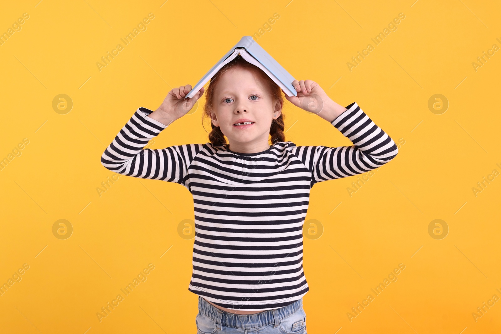 Photo of Smiling girl with book on yellow background