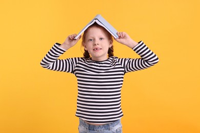 Photo of Smiling girl with book on yellow background