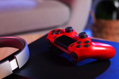 Photo of Video game console, wireless controller and headphones on table indoors, closeup