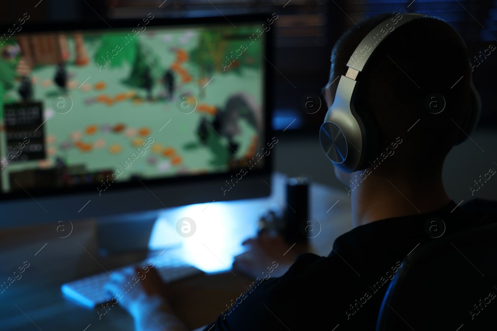 Photo of Man playing video games on computer at table indoors