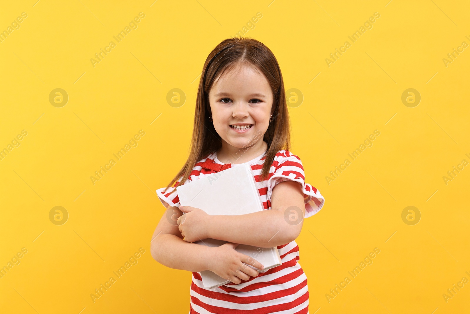 Photo of Cute little girl with book on orange background