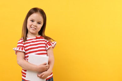 Cute little girl with book on orange background. Space for text