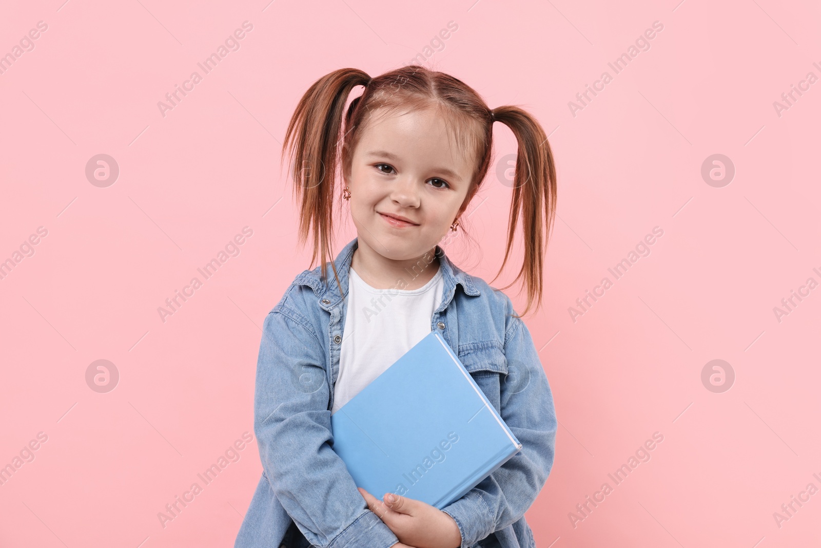 Photo of Cute little girl with book on pink background