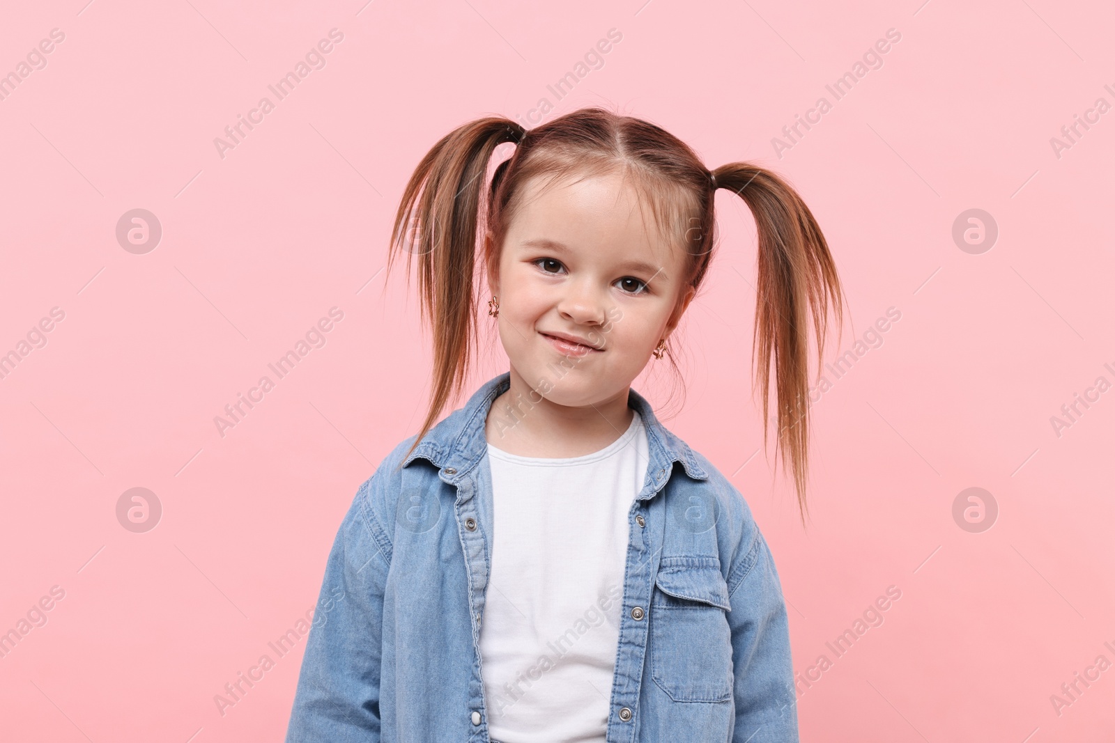 Photo of Portrait of cute little girl on pink background