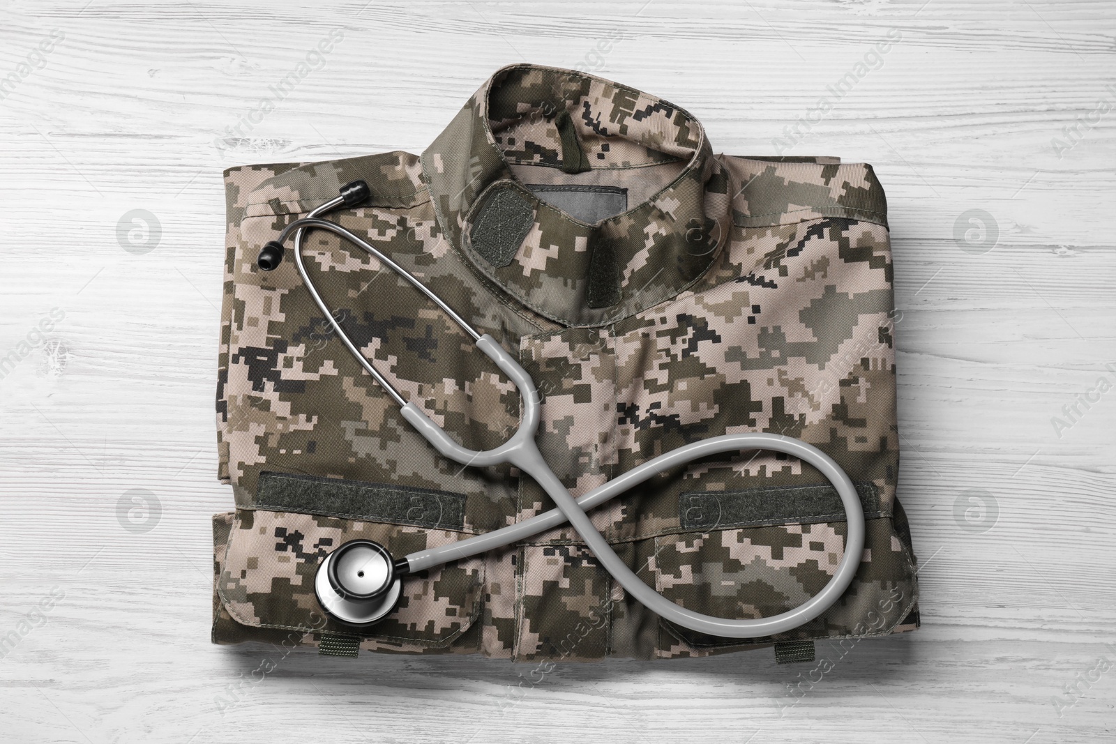 Photo of Stethoscope and military uniform on white wooden background, top view