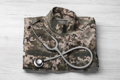 Stethoscope and military uniform on white wooden background, top view