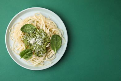 Photo of Tasty pasta with spinach, cheese and sauce on green table, top view. Space for text