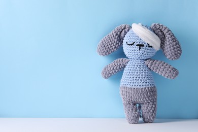 Photo of Toy bunny with bandage on color background, space for text