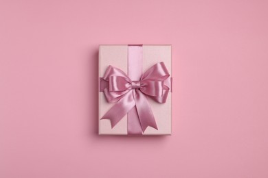 Photo of Beautiful gift box with color bow on pink background, top view