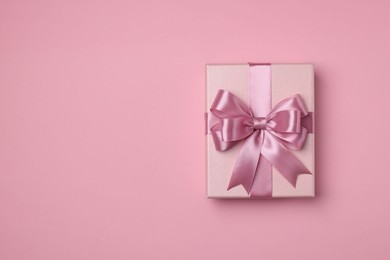 Photo of Beautiful gift box with color bow on pink background, top view. Space for text