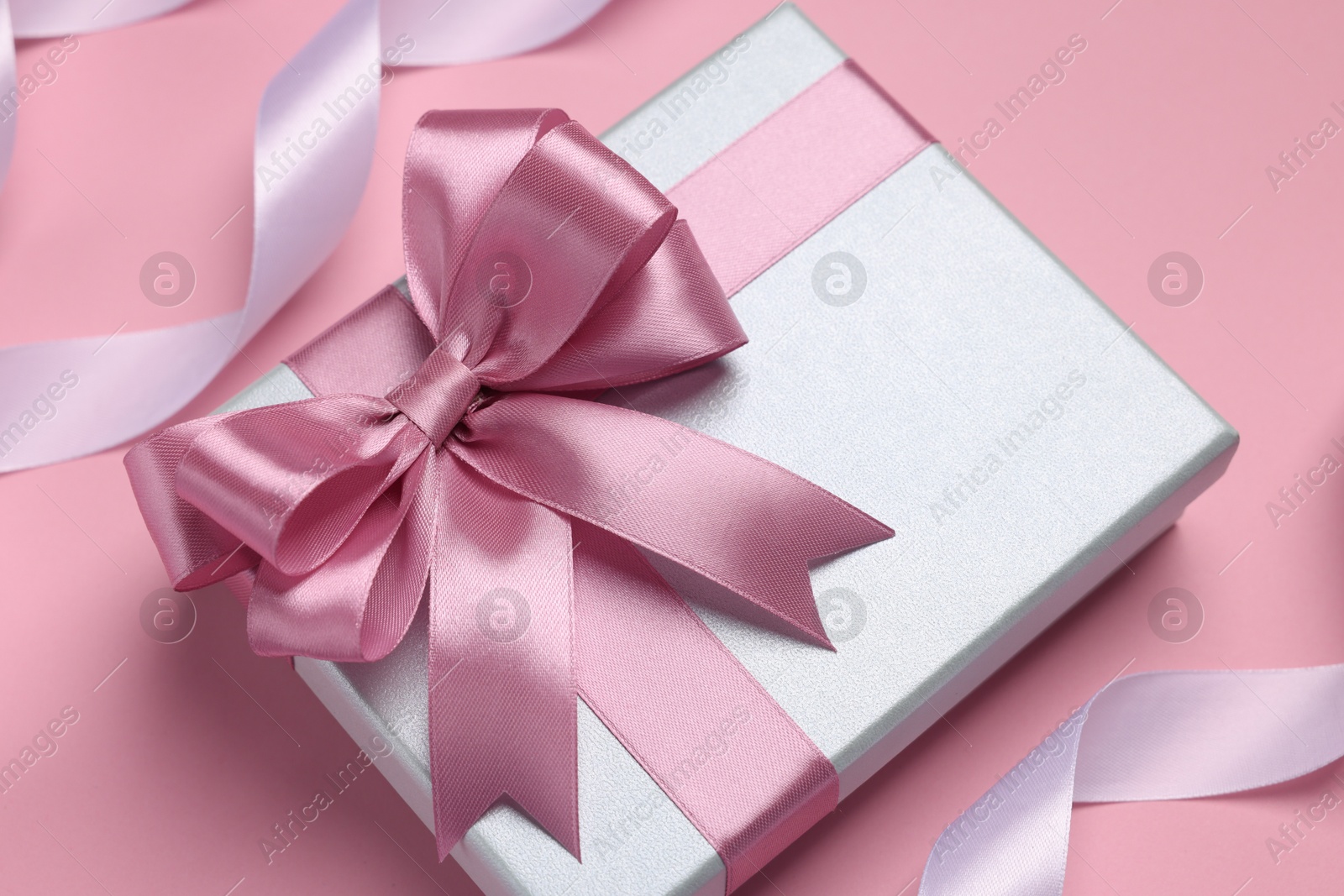 Photo of Beautiful gift box with color bow and ribbons on pink background